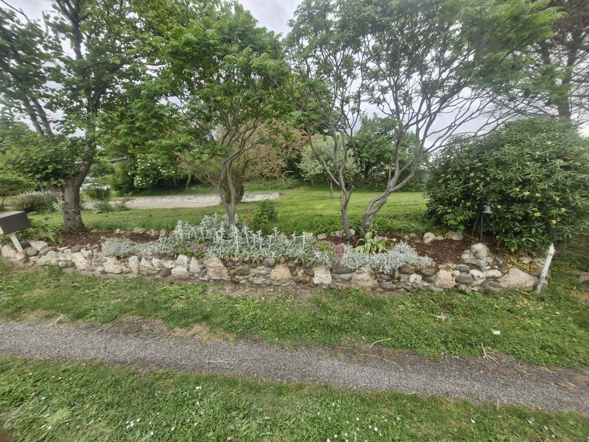 Massif paysager en pierres avec arbustes et vivaces conçu par lj dans un jardin verdoyant à gimont